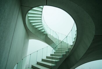 Obraz premium Modern spiral staircase with glass railing and concrete structure