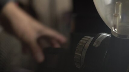 Cinematic scenes of a man used coffee bean grinder in coffee shop. Thai language on grinder means “instruction”. Selective focus and free copy space.