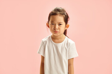 Frustrated Little Asian Girl Pursing her Lips from Resentment with a Gloomy Expression on Face...