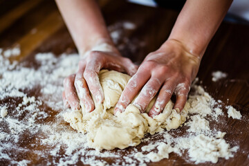 Chef kneading dough on kitchen table close up background.