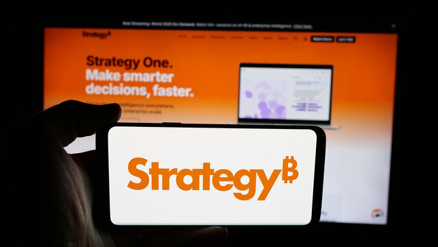 Stuttgart, Germany - 06-07-2025: Person holding cellphone with logo of US company MicroStrategy Inc. on screen in front of webpage. Focus on phone display.