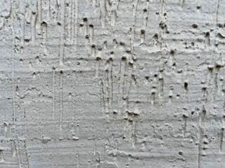 rough white stucco wall with weathered pitted texture and subtle vertical drip patterns ideal for grunge graphic design, urban backdrop, or abstract branding element

