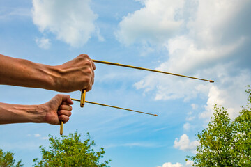 Dowsing with metal L rods in hands - a modern dowser's tool. Two dowsing rods for practicing radiesthesia. An ancient method, not proven by science