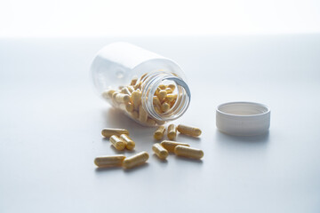 A jar with pills inside lies on a white background with reflection. Hyaluronic acid, collagen,...