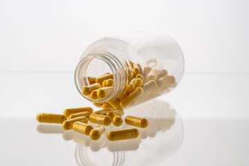 A jar with pills inside lies on a white background with reflection. Hyaluronic acid, collagen,...