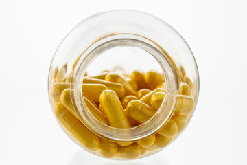 A jar with pills inside lies on a white background. Hyaluronic acid, collagen, vitamins or barberry...