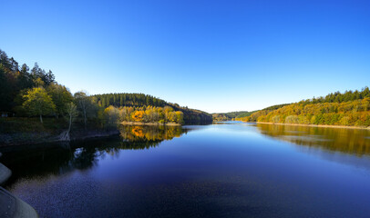 Obraz premium View of the Oleftalsperre Dam and the surrounding landscape. Nature at the lake near the Eifel National Park near Hellenthal in the Hohes Venn-Eifel Nature Park. 