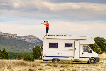 Woman traveling with caravan, taking photo from rv roof