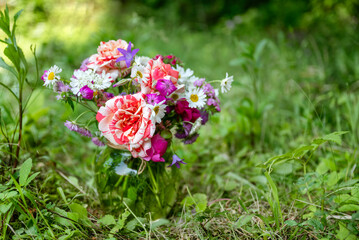 Beautiful bouquet of summer flowers in glass vase in a green garden 