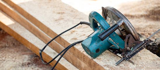 Electric circular saw on timber stack. Work tool for carpentry in a wood workshop used for cutting...