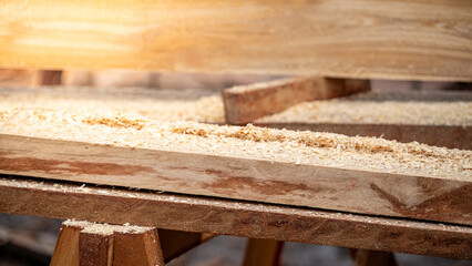 Sawdust heap spreading on timber on workbench in the wood workshop. Wooden dust from planing and sawing timber. Wood production waste. lumber industry concept