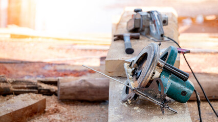 Electric circular saw on timber stack in a wood workshop. Work tool for carpentry used for cutting wooden plank or board. Lumber industry concept