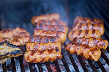 (Mici), traditional Romanian meat dishes on a grill during the cooking