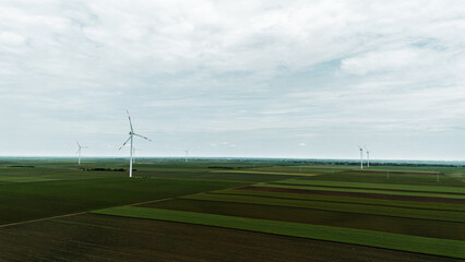 Aerial view of wind turbines on vast green fields in Vojvodina, Serbia, during springtime, with...