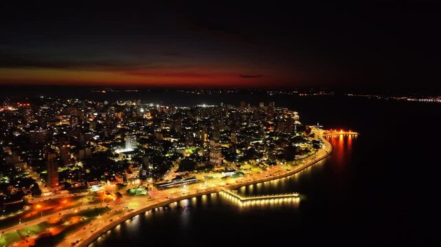 Dramatic aerial night view of lit coastline with beautiful urban light trails at the city of Posadas, Misiones, Argentina.