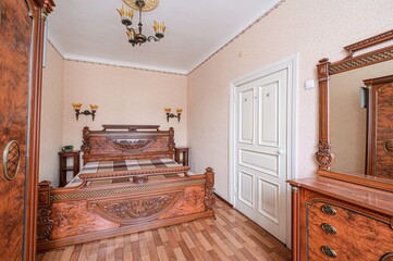 bedroom with ornate wood furniture including a large bed, wardrobe, and dresser with a mirror. The...