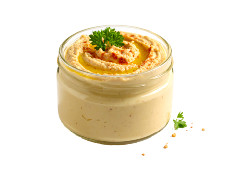 Glass jar of creamy hummus garnished with parsley, paprika, and olive oil on transparent background