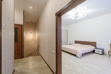 view into a bedroom from a hallway. The bedroom has a bed, nightstand, and closet. The hallway has a staircase and a wooden door