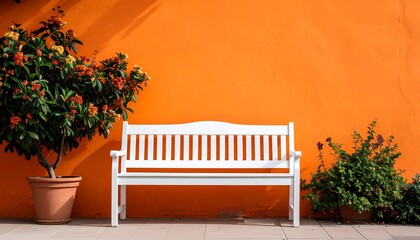 White bench in front of orange wall with flowers with outdoor seating, and travel concept.