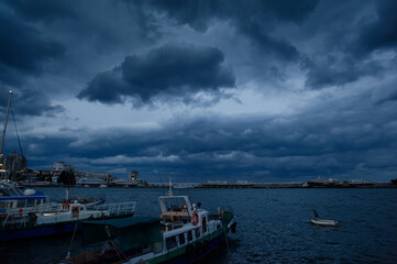 Dramatic Coastal Scene with Boats and Overcast Skies at a Harbor