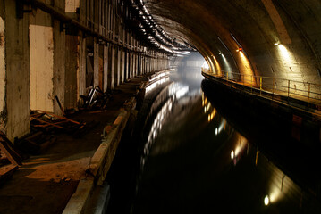 Dimly Lit Underground Tunnel with Water Reflection and Industrial Ambiance
