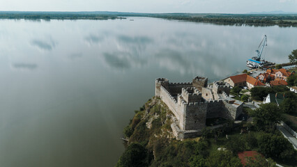 Naklejka premium Drone view of Ram Fortress on a rocky hill above the Danube River in Serbia. Impressive medieval fortification with panoramic view of the water and surrounding nature