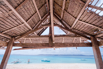 Rustic Beachfront Hut Overlooking Clear Blue Water and Fishing Boats