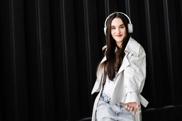 Confident Young Woman in Headphones Against Black Wall