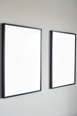 Two elegant empty frames are artfully placed on a minimalist wall, ideal for showcasing cherished art or photos