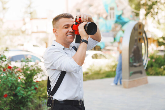 A middle-aged man with a camera in a red protective case takes a photo. 