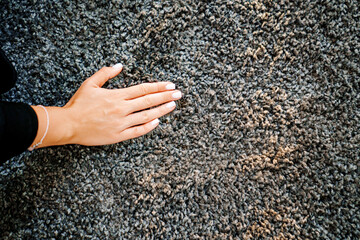 a woman's hand touching the grey Interior pile carpet 