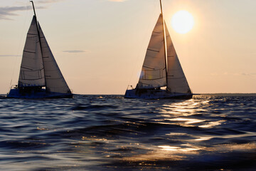 Sailing regatta in the Gulf of Finland at sunset, two sailing yachts competing in a race, splashing...
