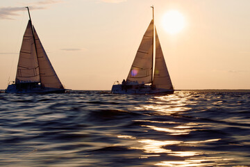 Two sailboats are moving at high speed at sunset, sailing regatta in the Gulf of Finland at sunset,...