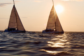 Sailing regatta in the Gulf of Finland at sunset, two sailing yachts competing in a race, splashing...