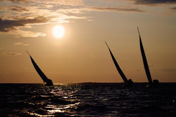 Sailing regatta in the Gulf of Finland at sunset, few sailing yachts competing in a race, splashing...