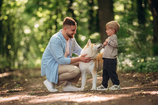 Sitting, playing with pet. Father with son and dog are in the forest