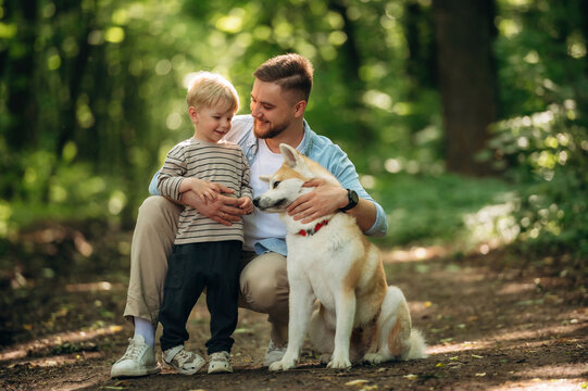 Positive facial expression, sitting. Father with son and dog are in the forest