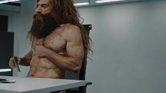 Primeval man feeling confused and annoyed while working with computer in modern office, trying to use a stone tool as a mouse and experiencing difficulties adapting to new technologies