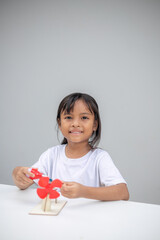 A young girl explores renewable energy outdoors by playing with a wind turbine toy,