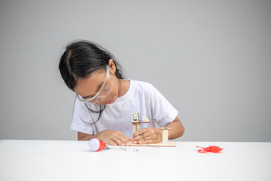 A young girl explores renewable energy outdoors by playing with a wind turbine toy