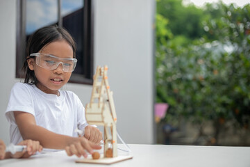 A young girl learns basic engineering by playing with a hydraulic excavator toy