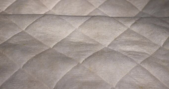 old cotton fabric from an old used mattress, part of the fabric from which the mattress is sewn after prolonged use, close up