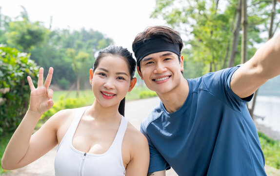 Smiling couple take a selfie outdoors after a run woman holds up three fingers for the camera
