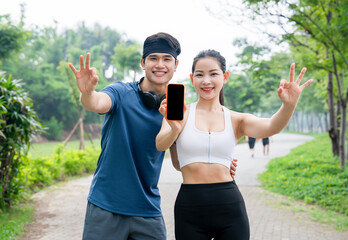 Athletic duo celebrating fitness milestone with phone display making peace signs on outdoor trail
