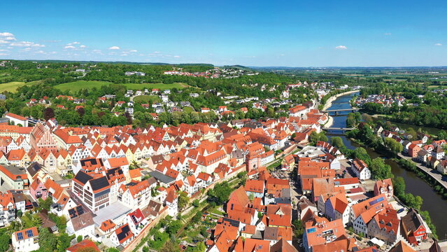 Luftaufnahme von Donauw&ouml;rth mit roten D&auml;chern, historischen Geb&auml;uden und einem markanten Turm, eingebettet in eine gr&uuml;ne Landschaft. Die Stadt bietet eine charmante Kulisse.