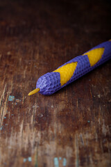 Violet yellow textured natural bee wax candle on rustic wooden table background. closeup shot, copy...
