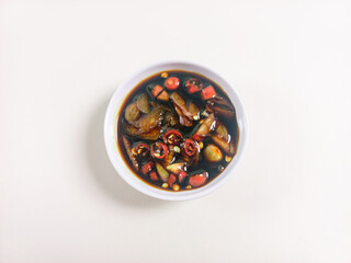 Sweet soy sauce chili sauce with sliced red cayenne pepper served on a white plate placed on a...