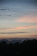 A serene landscape features a soft twilight sky with pastel shades of pink and blue. 