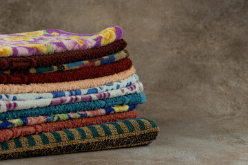 Lots of terry towels on textured background. Bathroom towels stacked in a pile.