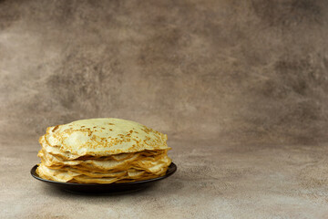 A stack of thin pancakes on a textured background. Pancakes for Maslenitsa. There is space for text.